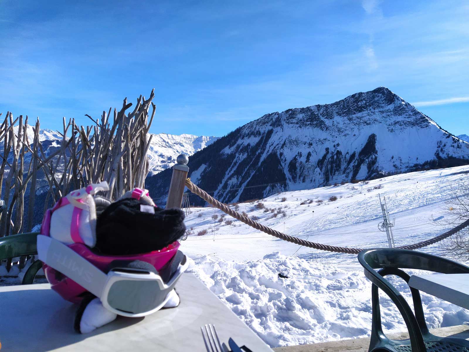Winters berglandschap getrokken vanop terras, met skihelm en bril op tafel.